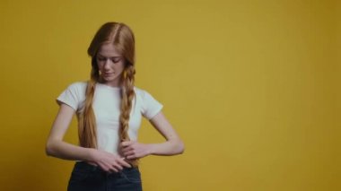 Şirin bir kadın sarı stüdyo duvarında saçını düzeltiyor.