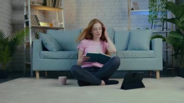 Genç öğrenci yerde tablet kullanarak ve kahve içerek online dersler alıyor.