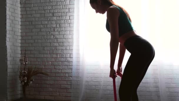 Mujer caucásica está teniendo una sesión de fitness en casa usando bandas elásticas — Vídeo de stock