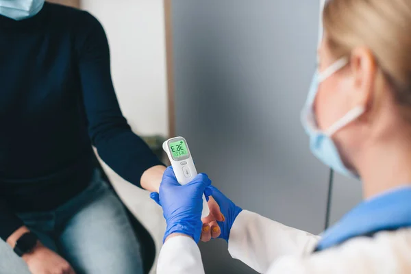 Close up photo of a caucasian senior doctor using a electronic thermometer to measure patient temperature — Stock Photo, Image