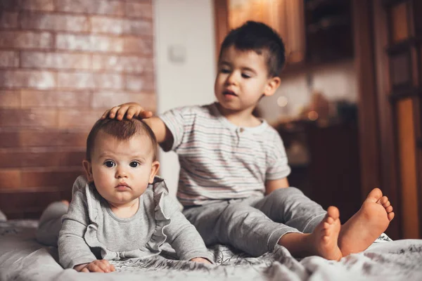 Frère et sœur nouvelle-née assis sur le canapé ensemble et jouant — Photo