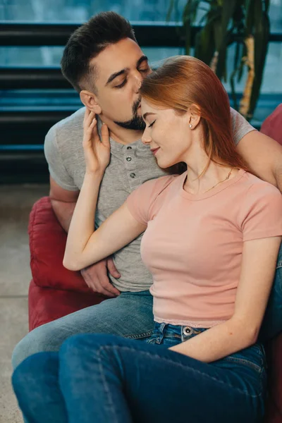 Jeune couple embrasser sur un canapé tandis que la femme roux est couché sur son amant — Photo