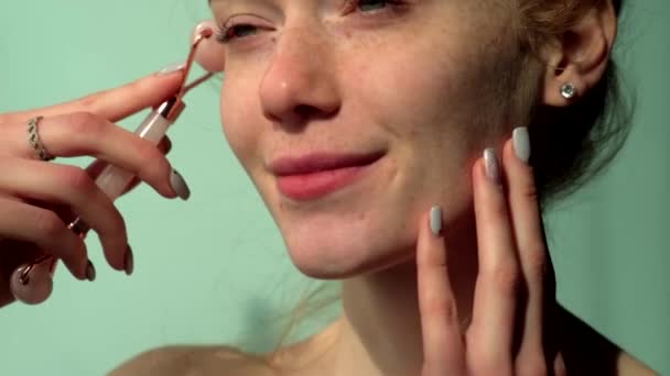 Ingwerfrau mit Sommersprossen lächelt, während sie ihr Gesicht mit einem Derma-Roller massiert — Stockvideo