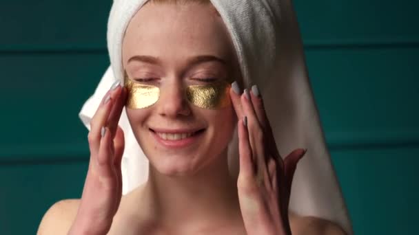 Ginger woman with freckles is wearing golden eye patches smiling at camera — Stock Video