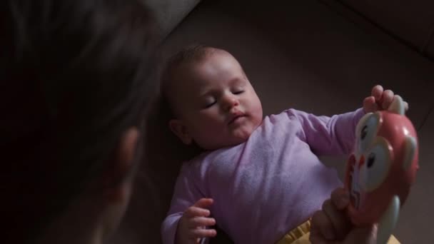 Adorable upper view video of a caucasian mother showing a toy to her daughter while going to bed — Stock Video