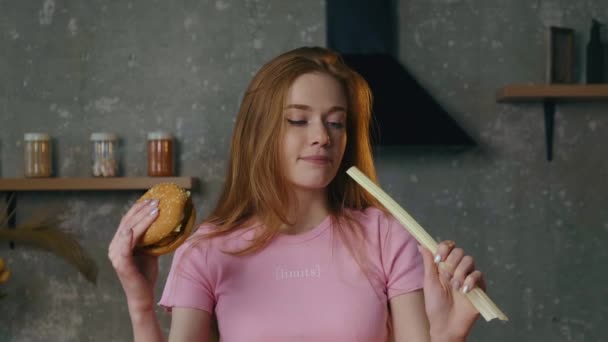 Caucasian woman is choosing natural food over fast food holding a burger and leek — Stock Video