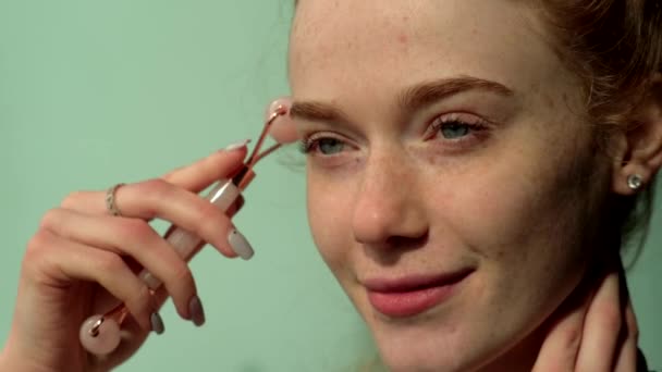 Ingwerfrau mit Sommersprossen massiert ihr Gesicht mit einem speziellen Gesichtsdermaroller — Stockvideo