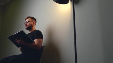 Kafkasyalı bir adamın sakallı ve gözlüklü bir kitaptan bir şeyler açıklayan videosu.