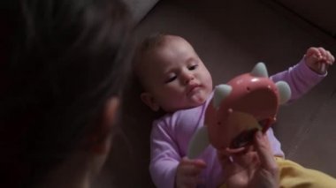 Kafkasyalı bir annenin yeni doğmuş bebeğiyle oynayıp ona plastik bir oyuncak göstermesinin videosu.