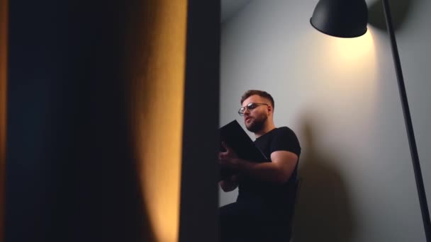 Homme caucasien ayant un appel vidéo tout en lisant un livre pendant certains cours — Video