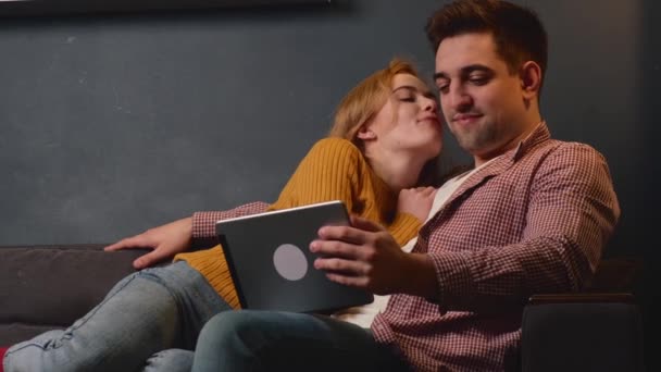 Імбир мила жінка з веснянками цілує свого хлопця, лежачи на дивані — стокове відео