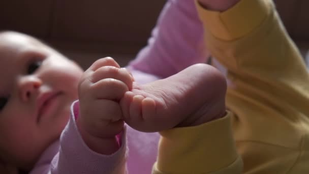 Nahaufnahme eines neugeborenen Babys, das seine Beine hält, während es jemanden ansieht — Stockvideo