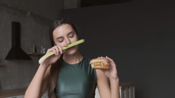 Donna caucasica sta mangiando un hamburger, mentre tenendo porro naturale in mano sorridendo dopo aver preso la decisione — Video Stock