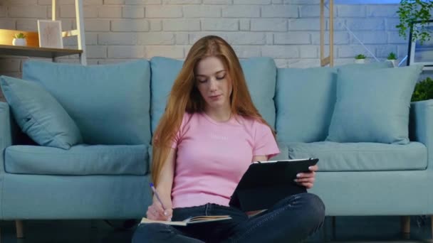Wanita berambut merah dengan bintik-bintik wajah sedang menulis topik selama video pelajaran di universitas — Stok Video