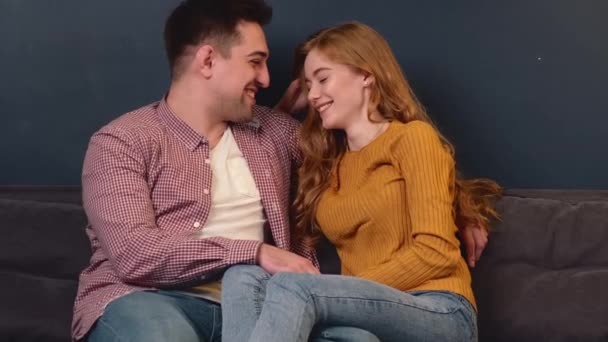 Чарівна пара посміхається один одному, лежачи на дивані разом — стокове відео
