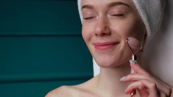 Adorable woman is massaging her freckled face with a derma roller smiling at home — Vídeos de Stock