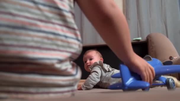 Видео, на котором маленький ребенок играет с маленькой сестрой на диване с пластиковыми игрушками — стоковое видео