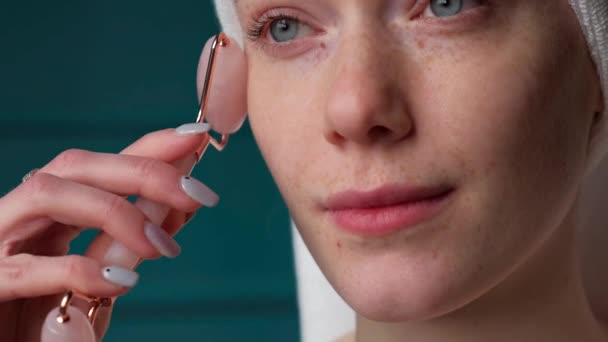 Close up video of a freckled woman is using a derma roller on her face smiling — Vídeos de Stock