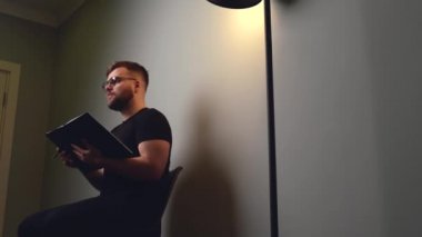 Kafkasyalı adam lamba ışığında kitap okurken çevrimiçi dersler veriyor.