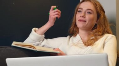 Kızıl kadın evde çalışırken bilgisayar kullanıyor. Video görüşmesi sırasında biriyle konuşuyor.