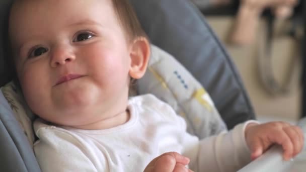 Piccolo bambino sta sorridendo a sua madre mentre mangia bacche sdraiato in una poltrona bambino — Video Stock