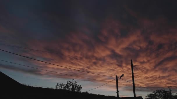 Cielo nocturno con nubes de colores durante una puesta de sol de verano en un pueblo — Vídeos de Stock