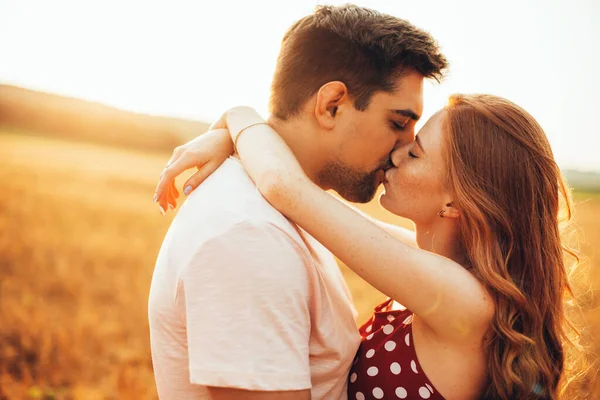 Close up foto de uma mulher de gengibre com sardas beijando seu amante em um campo ensolarado de trigo abraçando — Fotografia de Stock