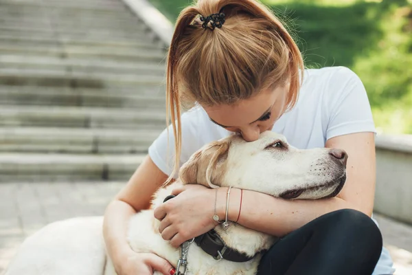 Femme caucasienne embrasse son labrador l'embrasser lors d'une promenade dans le parc — Photo