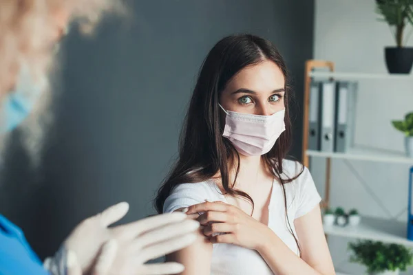 O femeie adorabilă se uită la cameră în timp ce ia vaccinul împotriva virusului corona purtând o mască la spital — Fotografie, imagine de stoc