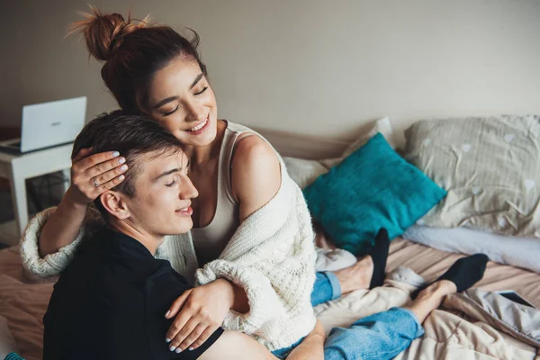 Liebenswerte Frau liegt auf ihrem Liebhaber und umarmt ihn im Bett, während sie einen Strickpullover trägt — Stockfoto