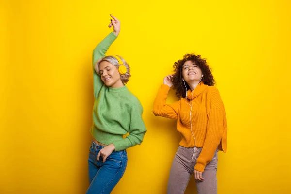 Tanzstudio. Schöne Schwestern mit lockigem Haar, die Musik hören. Internettechnologie. Studiozimmer mit gelber Farbe. — Stockfoto