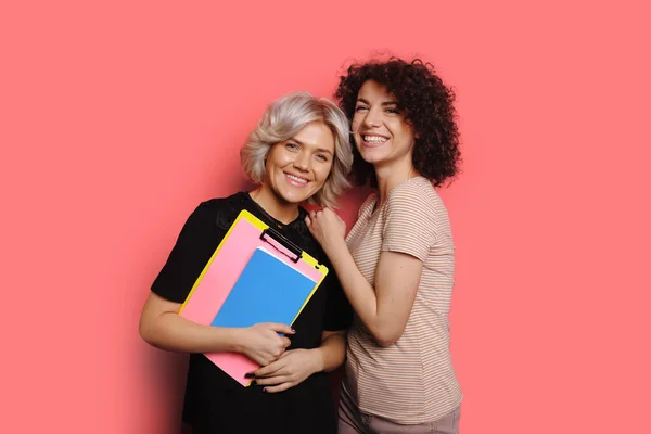 Stilvolles Porträt einer lockigen Schwester, die Schulmappen in der Hand hält. Hübsche junge Frau. Glückliches Familienkonzept. — Stockfoto