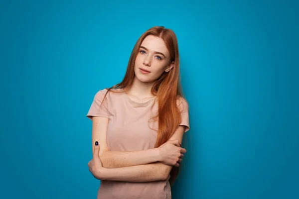 Mujer pelirroja con pecas en la pared de un estudio. Persona sobre fondo azul. Traje de mujer. Chica de moda sonriendo. — Foto de Stock