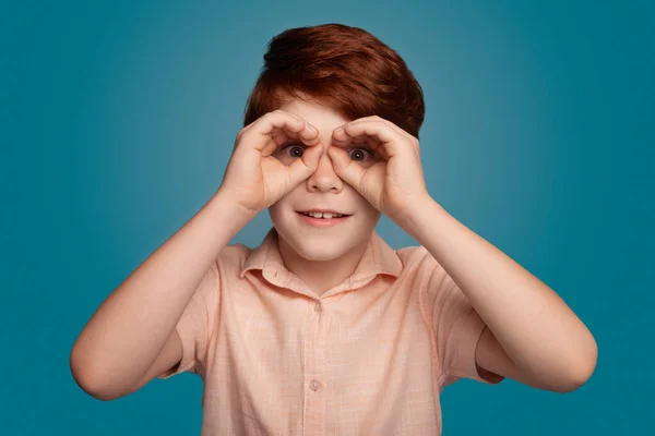 Ginger boy gestos binóculo sinal no estúdio em estilo moderno. Modelo de moda. — Fotografia de Stock