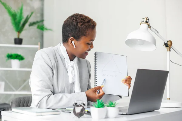 Modern portrait. People working. Black teacher explain to laptop from a book.