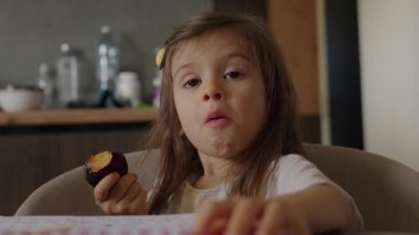 Kız keki mutlu ve mutlu bir şekilde yiyor, kız da lezzetli kekinin tadını çıkarıyor.