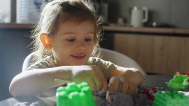 Güzel bir kız bloklarla oynuyor, beyaz bir kız gülümsüyor ebeveynleri oyun sırasında ona nazikçe dokunuyor.