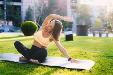Bir kadın coşkulu bir parkta yoga pozu verip zihin ve beden için rahatlık ve rahatlık sağlıyor.
