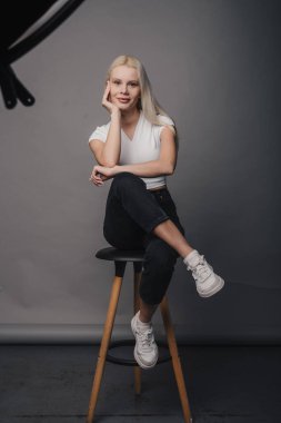 Zarif ve özgüvenli bir şekilde oturan ve kendine güvenen genç bir kadının son moda portresi farklı bir tarz duygusu yayıyor.