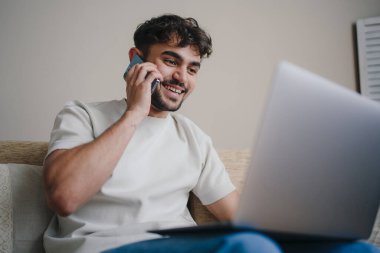 Genç tasarımcı evde rahat çalışıyor, rahatlamış profesyonel müşteri tartışması yapıyor.