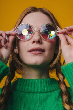 Renkli gözlükler ve neşeli tavırlar, Kaleydoskop gözlükleri ve canlı stil detaylarıyla eksantrik bir kadın.