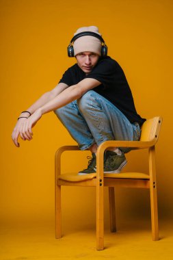 Sanatsal konsantrasyonu aktarmak için canlı stüdyo içindeki sandalyeye düşünceli bir şekilde yerleştirilmiş kişi.