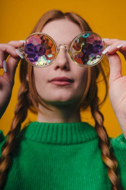 Parlak aksesuarlı şık bir kadın, ışıl ışıl gözlüklü ve örgülü saçlı bir bayan.