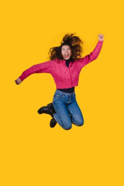 Neşeli bir kadın süzülüyor, coşkulu bir kadın gündelik giysiler içinde sevinçle sıçrıyor.