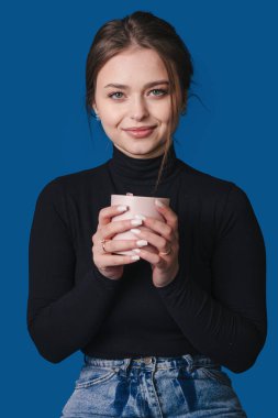 Yaratıcı tasarımcı kahve molası veriyor, siyah balıkçı yakalı kadın iş yerinde kahve içiyor.