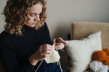 Kadın konforlu yastıklar ve güneş ışığı altında el yapımı tekstil desenleri üzerinde huzur içinde çalışıyor.