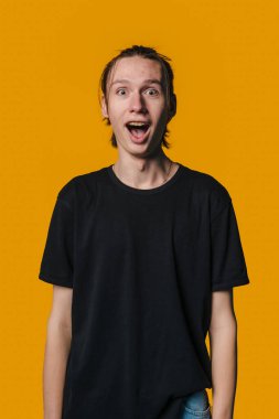 Heyecanlı adam tepki veriyor, şaşırmış yüz ifadesi olan adam canlı turuncu arka planda şok gösteriyor.