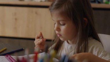 Genç bir kadın odakla çizer, genç bir kadın çizim defterini ılık doğal ortamında boyamak için kalemleri dikkatle kullanır.