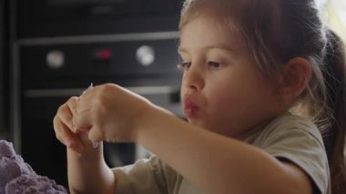 Küçük tanecikleri incelikle modelleyen genç bir kız dikkatli bir şekilde minyatür kum oluşumları yapıyor.