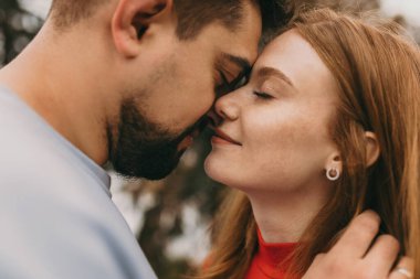 Yakından öpüşmek üzere olan çift, gözleri kapalı ve yüzleri iki santim aralıklı, yüze nazik dokunuşlar ve yumuşak sıcak tonlarda, sinematik
